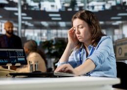 funcionária em mesa de escritório com aspecto de cansaço físico e mental