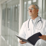 médico de jaleco em corredor segurando uma pasta