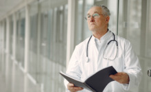 médico de jaleco em corredor segurando uma pasta