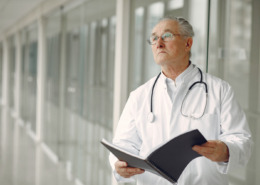 médico de jaleco em corredor segurando uma pasta