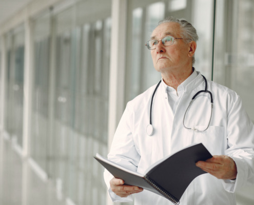 médico de jaleco em corredor segurando uma pasta