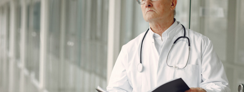 médico de jaleco em corredor segurando uma pasta