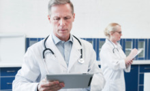 médico de jaleco branco olhando prancheta