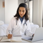 médica sentada em consultório preenchendo formulário