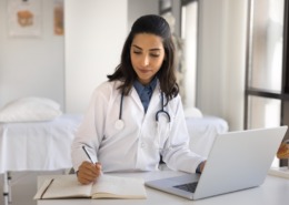 médica sentada em consultório preenchendo formulário