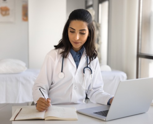 médica sentada em consultório preenchendo formulário