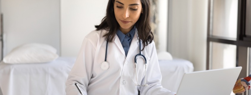 médica sentada em consultório preenchendo formulário