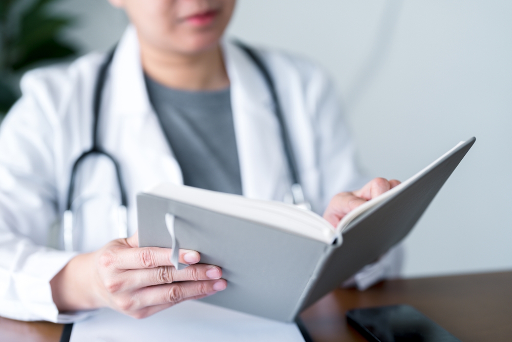 medica em pé analisando prancheta