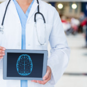 médico em pé, de jaleco branco com tela de tablet em mãos