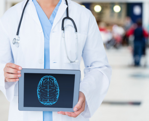 médico em pé, de jaleco branco com tela de tablet em mãos