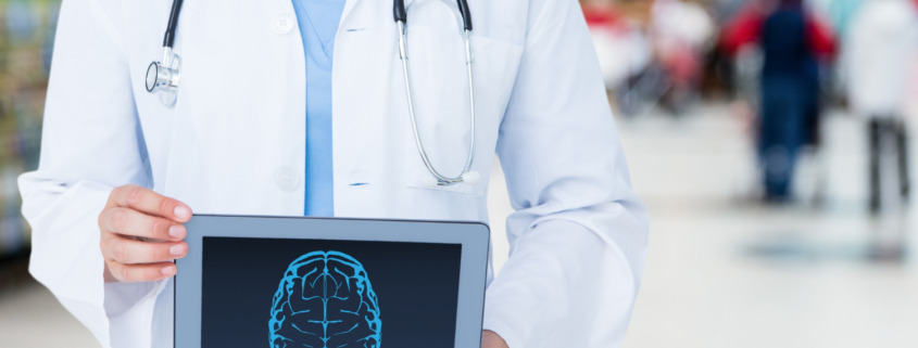 médico em pé, de jaleco branco com tela de tablet em mãos