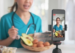 médica na cozinha, com legumes e gravando vídeo no celular