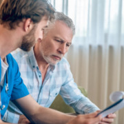 médico explica algo a homem sentado em sofá