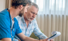 médico explica algo a homem sentado em sofá