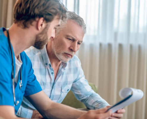 médico explica algo a homem sentado em sofá
