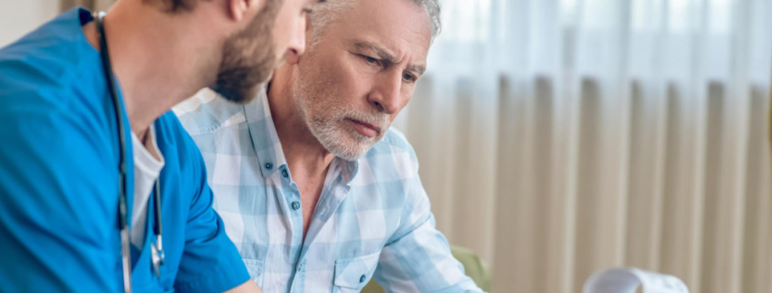 médico explica algo a homem sentado em sofá