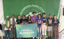 grupo de pessoas reunidas para foto em palco com uma bandeira verde ao fundo
