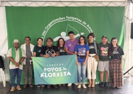 grupo de pessoas reunidas para foto em palco com uma bandeira verde ao fundo