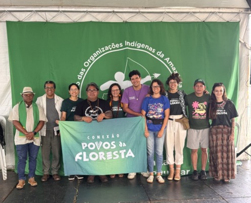 grupo de pessoas reunidas para foto em palco com uma bandeira verde ao fundo