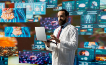 médico em pé na sala rodeado de telas com dados e gráficos digitais, simbolizando a tecnologia