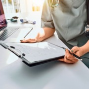 profissional de saúde em mesa de trabalho com formulário em mãos