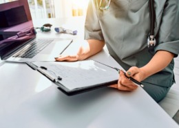 profissional de saúde em mesa de trabalho com formulário em mãos