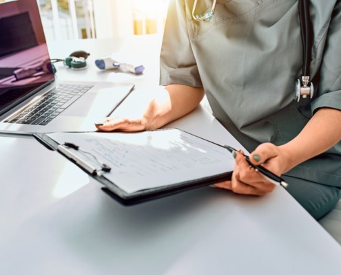 profissional de saúde em mesa de trabalho com formulário em mãos