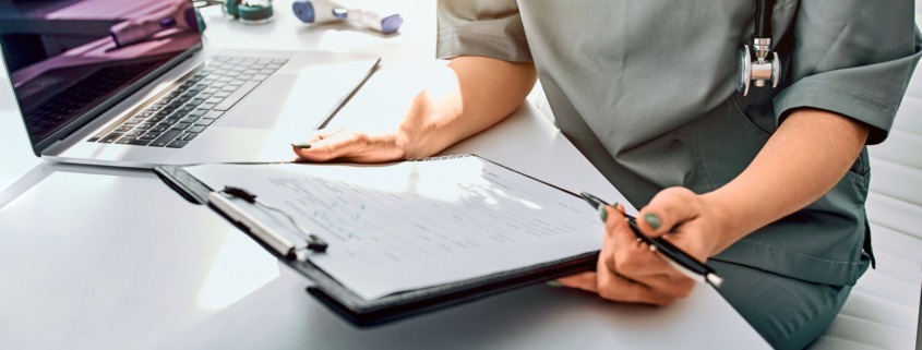 profissional de saúde em mesa de trabalho com formulário em mãos