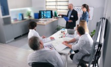 médicos reunidos em sala de reunião com gestor apresentando algo em tela