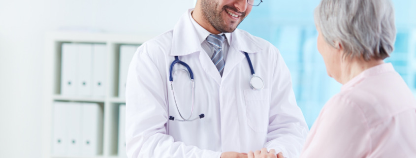 médico sorrindo comprimentando paciente idosa em consultório