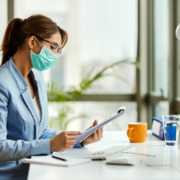 gestora de saúde em mesa de trabalho e utilizando máscara facial de proteção de virús