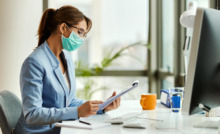 gestora de saúde em mesa de trabalho e utilizando máscara facial de proteção de virús