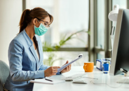 gestora de saúde em mesa de trabalho e utilizando máscara facial de proteção de virús