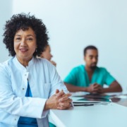 médica em mesa de reunião com outros médicos ao lado