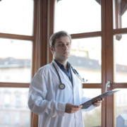 médico em corredor de clínica com parede de vidro ao fundo