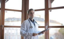 médico em corredor de clínica com parede de vidro ao fundo