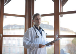 médico em corredor de clínica com parede de vidro ao fundo