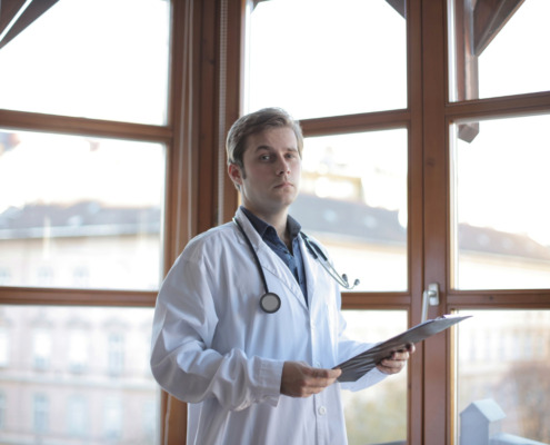 médico em corredor de clínica com parede de vidro ao fundo