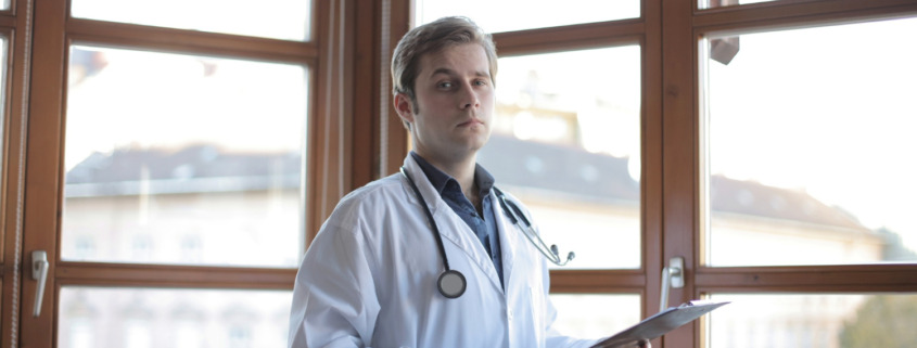 médico em corredor de clínica com parede de vidro ao fundo