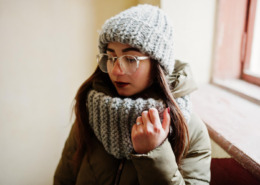 mulher com roupa de frio em área interna de casa