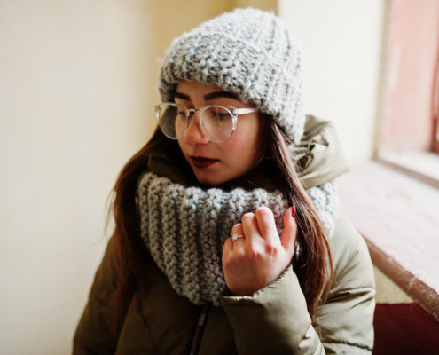mulher com roupa de frio em área interna de casa