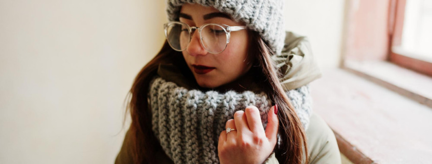 mulher com roupa de frio em área interna de casa
