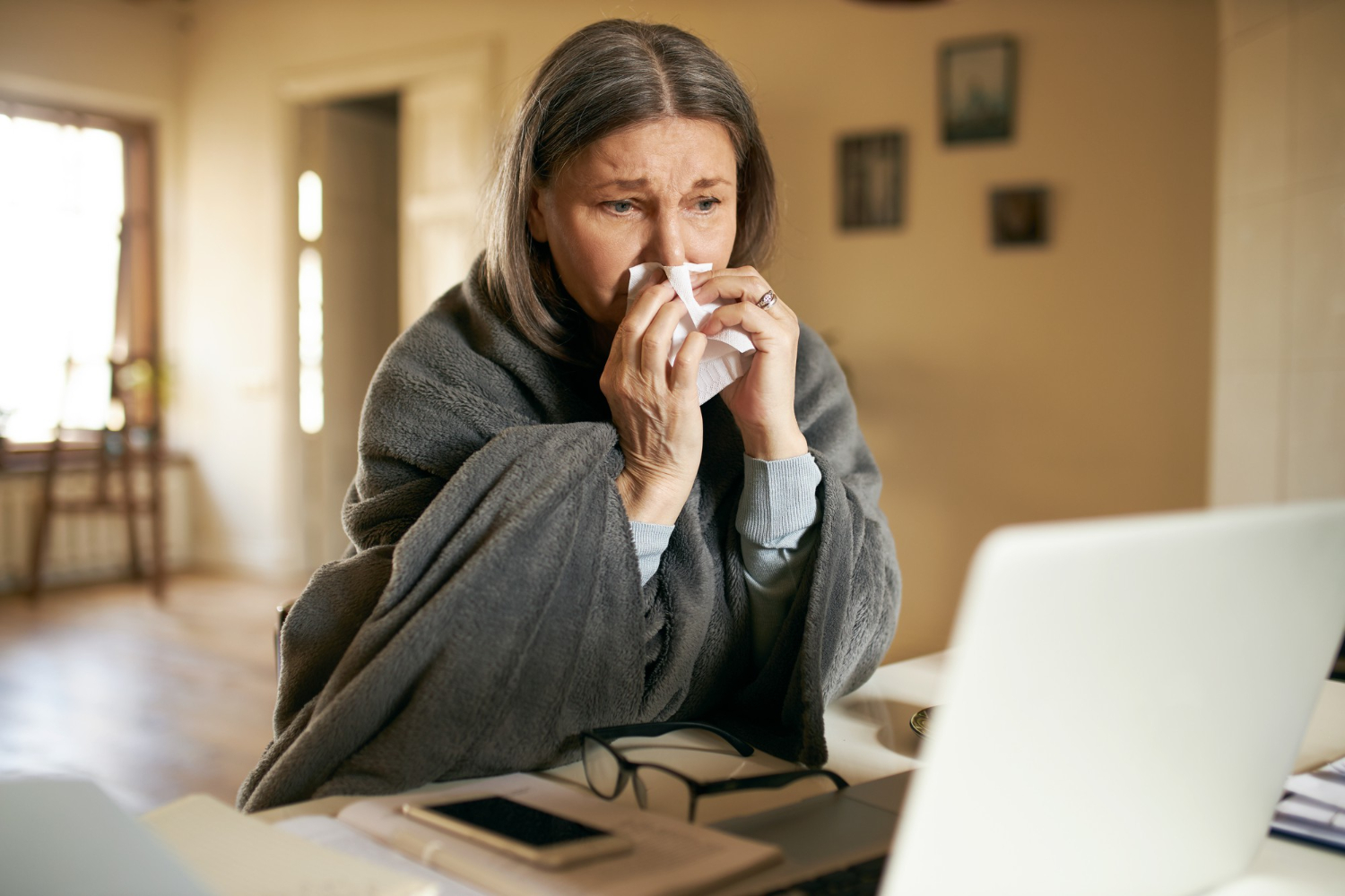 mulher com roupa de frio e enxugando o nariz com papel