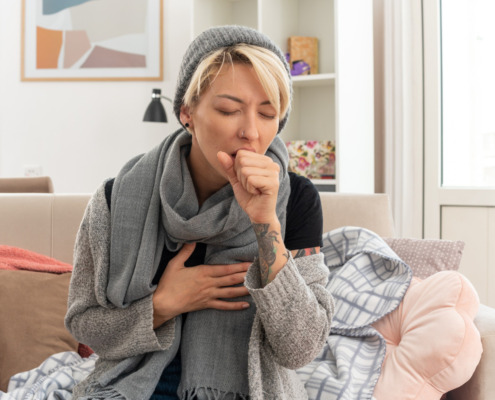 pessoa tossindo com roupa de frio em casa