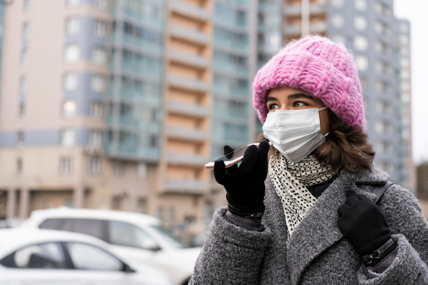 pessoa com roupa de frio andando pela cidade e falando ao celular