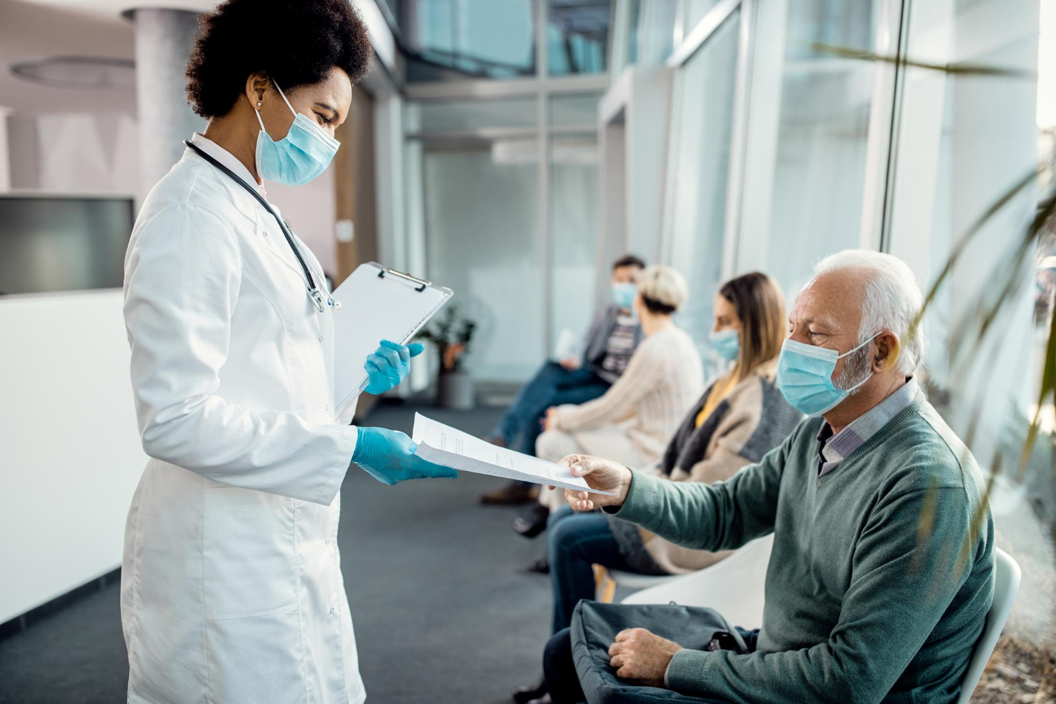 profissional de saúde conversando com pacientes em corredor de hospital