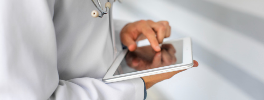 médico utilizando tablet com o dedo na tela