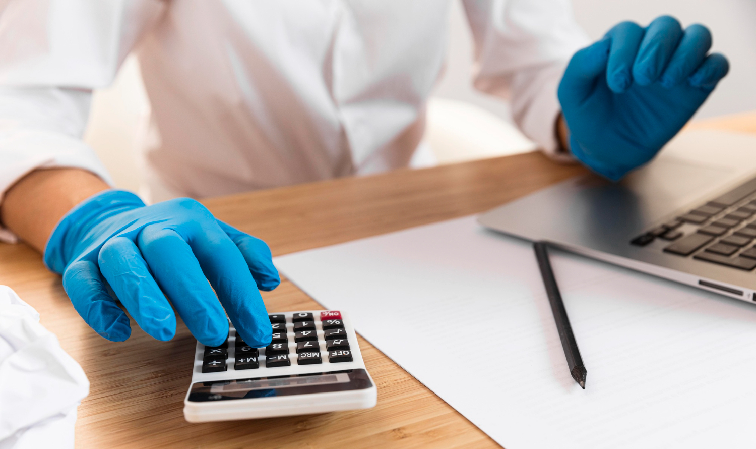 pessoa em mesa de trabalho utilizando calculadora portátil fazendo cálculos