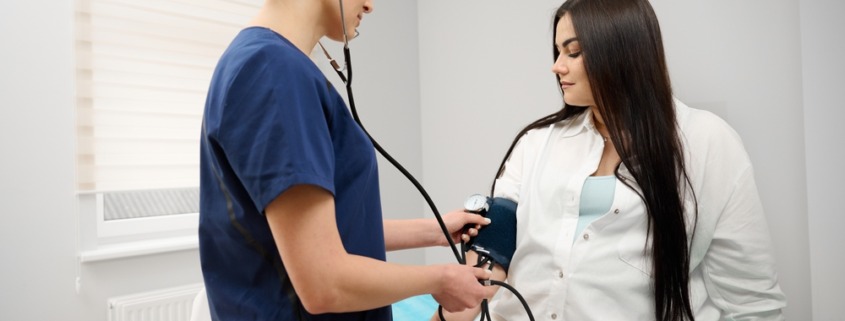 enfermeira medindo pressão arterial de paciente em maca