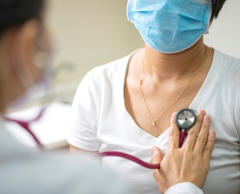 médica escuta o pulmão de paciente sentada